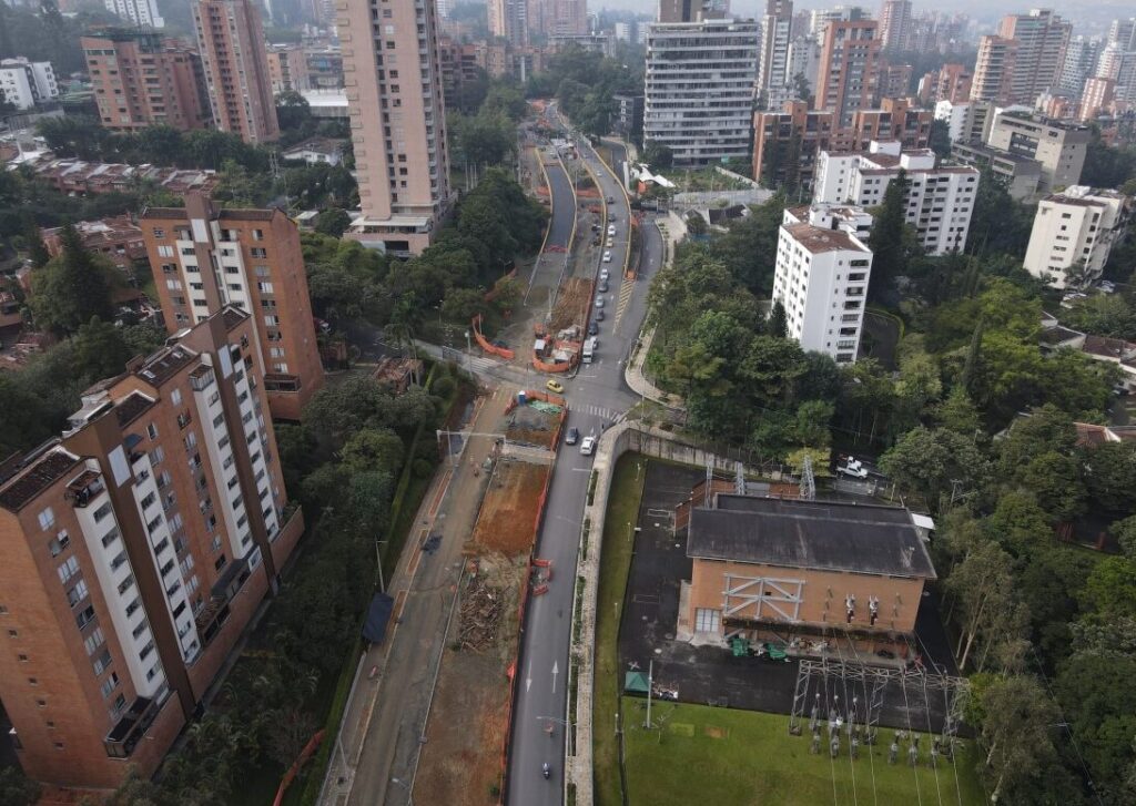 Vista aérea de avenida urbana con edificios de ladrillo y obra vial en construcción.