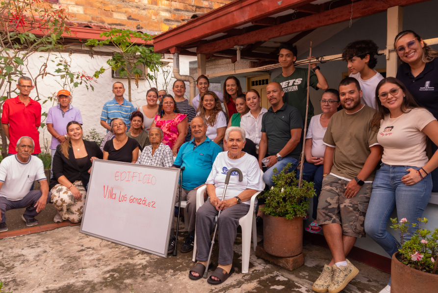 Foto grupal de la comunidad del chispero con la directora de Fonvalmed sosteniendo un tablero que dice Edificio Villa Los Gonzalez